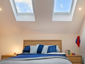 skylights above bed with blue and white sheets in auckland